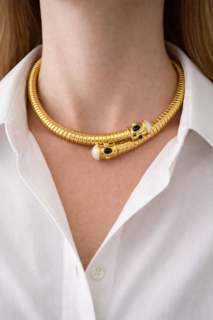 Colar dourado em formato de serpente usado por uma modelo de camisa branca